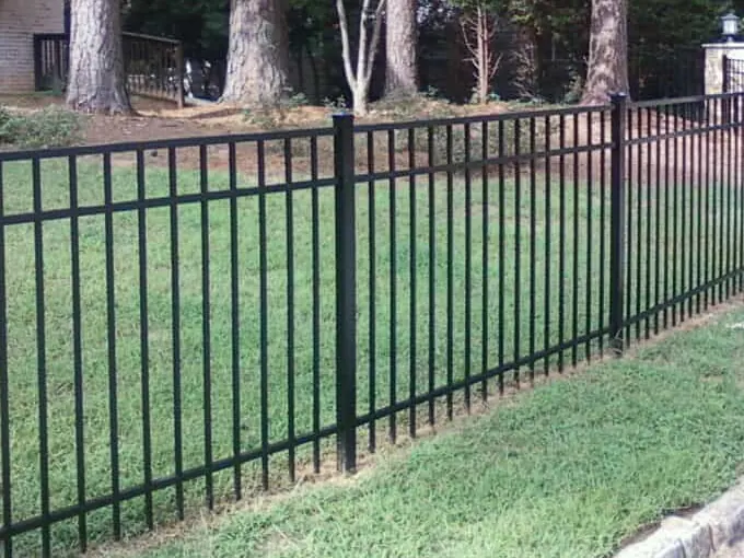 Black flat-top aluminum fence along a green front lawn
