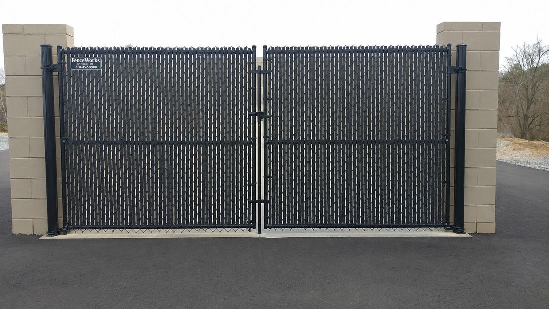 Black chain link dumpster enclosure with privacy slats