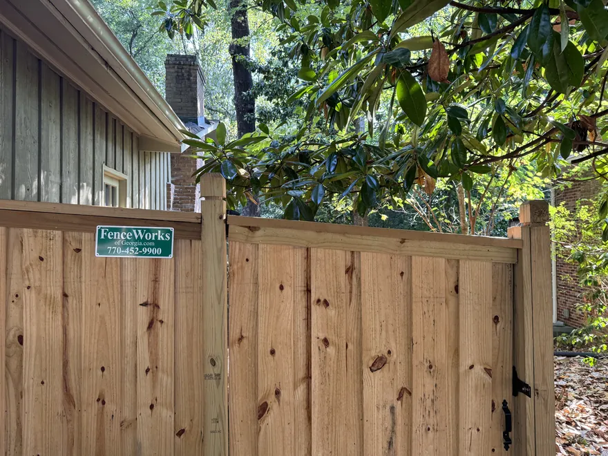 Board-on-board capped wood privacy fence with a FenceWorks of Georgia sign in Dunwoody, GA