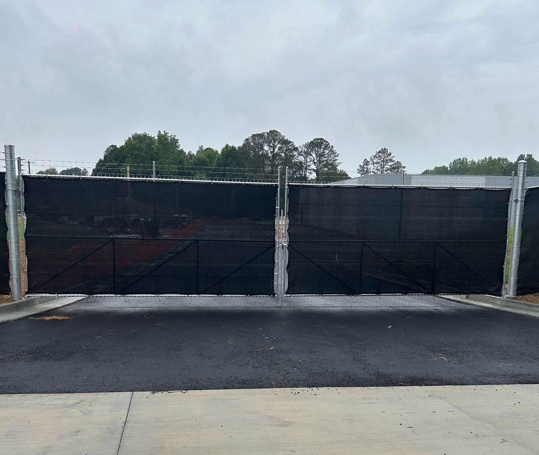 Secured commercial chain link perimeter with a barbed-wire double swing gate and windscreen