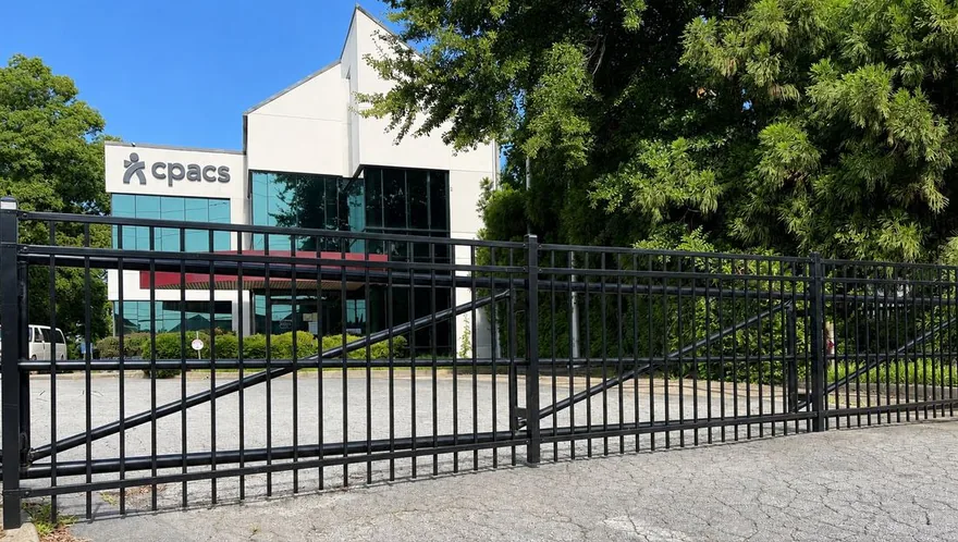 Black steel automated cantilever slide gate closed across a commercial driveway in metro Atlanta