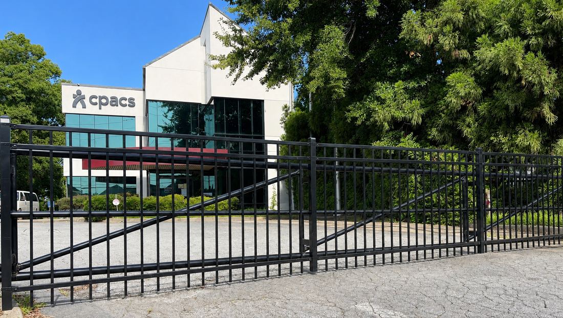 Black ornamental steel automated cantilever gate at a commercial office building