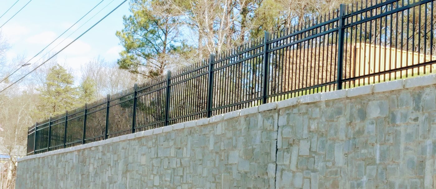 Ornamental metal spear-top fence atop a stone wall