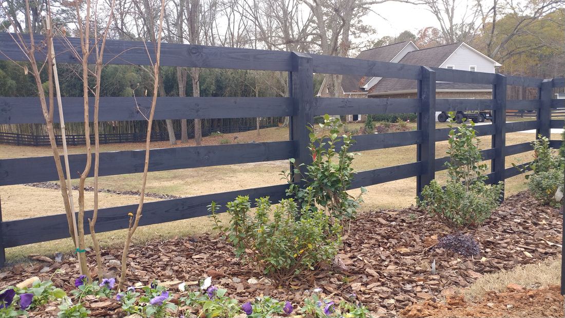 Black-stained wood four-rail ranch rail fence