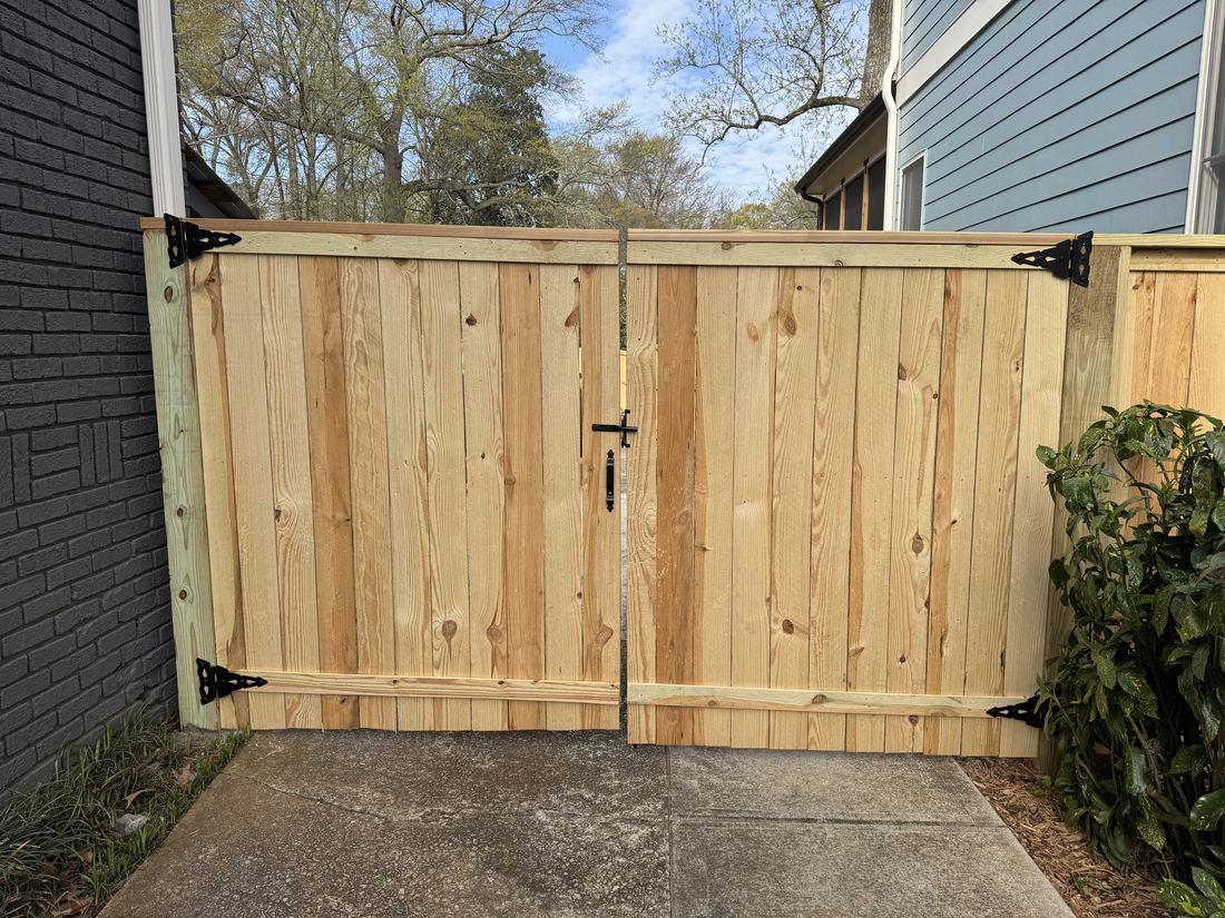Capped wood privacy double swing gate viewed from the street
