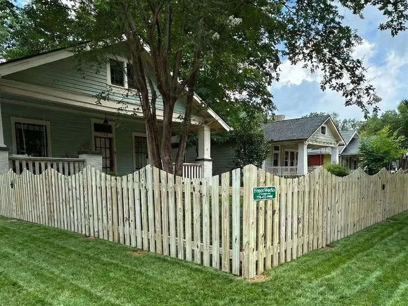 Scalloped wood picket fence in a front yard