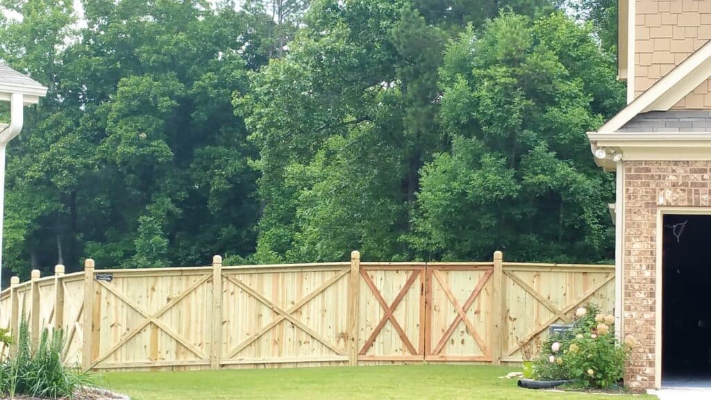 Wood residential crossbuck privacy fence with dado posts and double gate